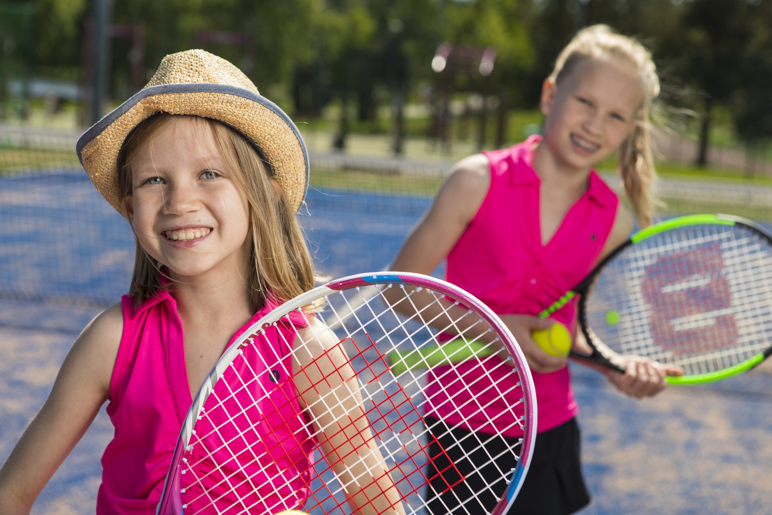 Kaksi nuorta tyttöä tenniskentällä.
