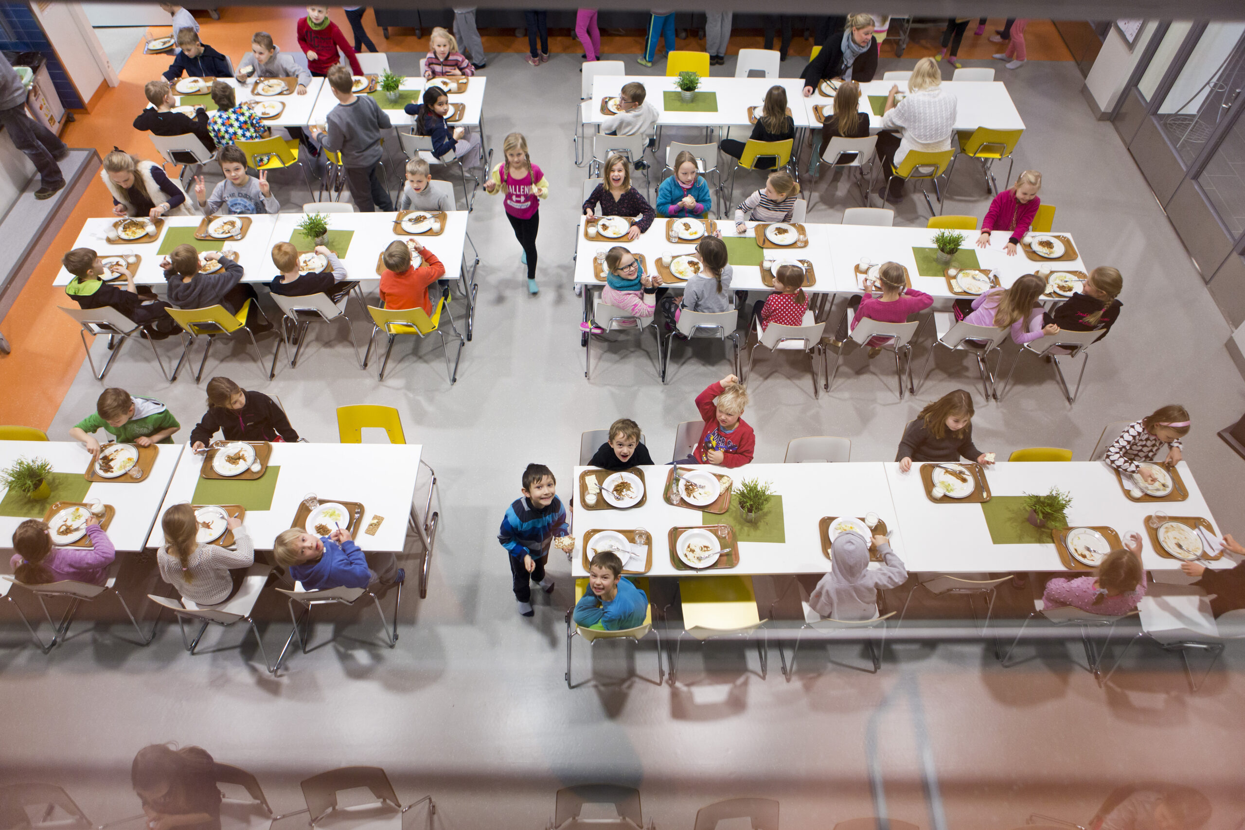 Ilmakuva Toivion koulun ruokasalista. Ruokapöydissä oppilaita ruokailemassa.