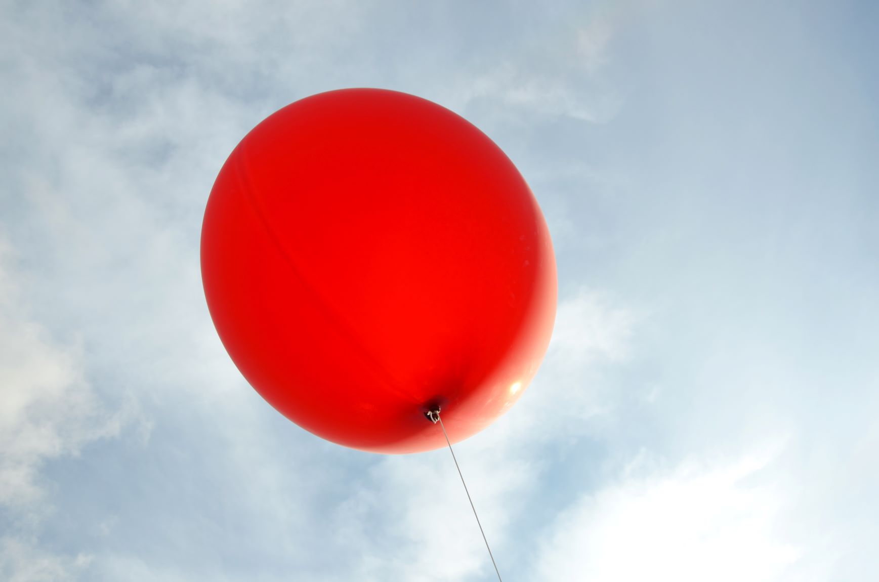 Punainen jätti-ilmapallo vaaleansininen taivasta taustanaan.